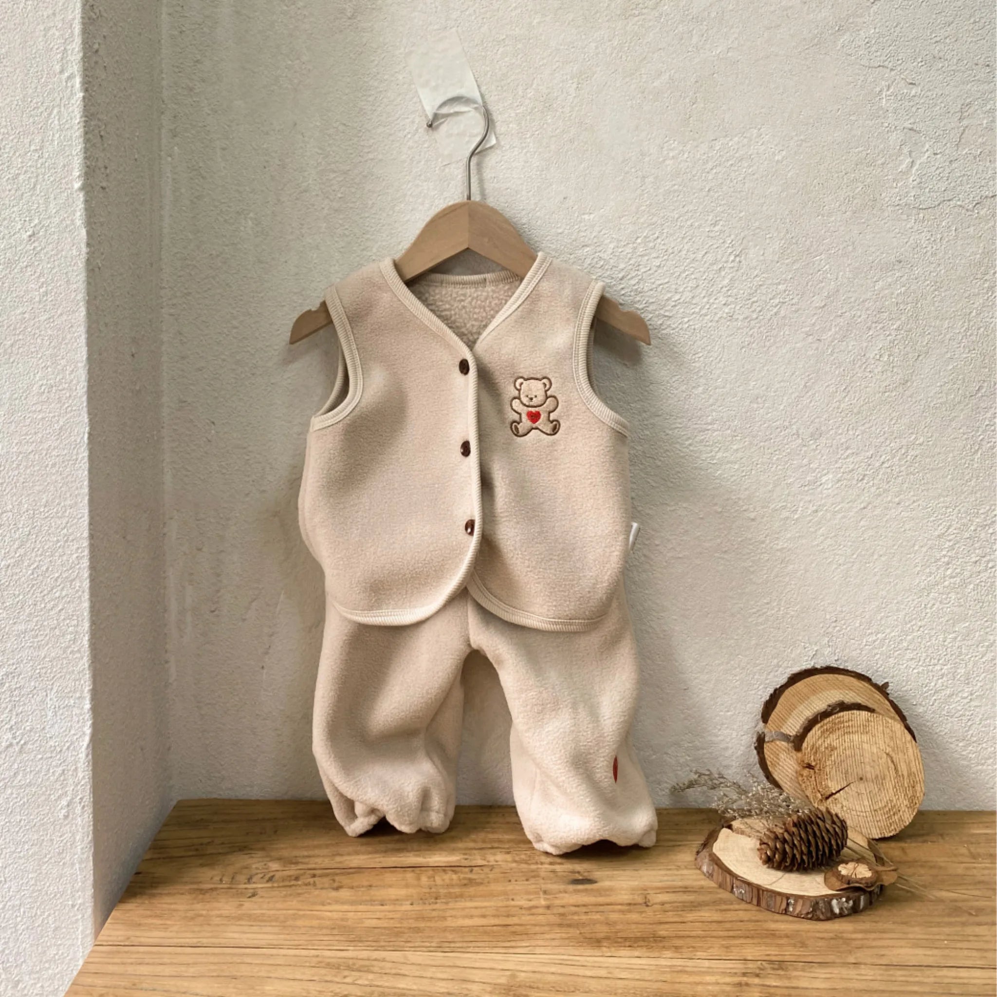Apricot baby teddy bear fleece vest and pants set on a wooden hanger, with bear and red heart embroidery on the chest